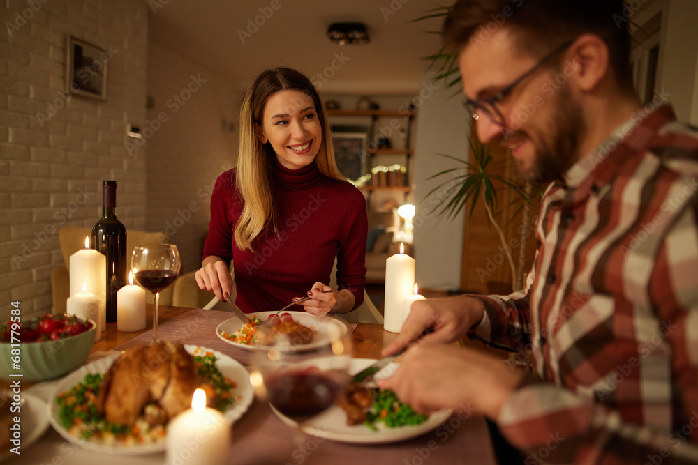 Beautiful couple having romantic dinner with candles and red wine at home