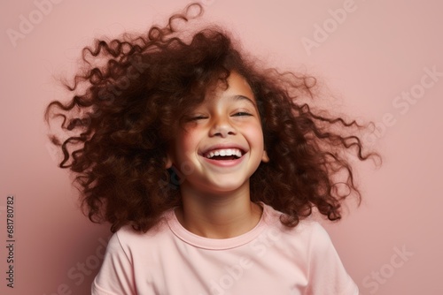 Portrait of a cute little girl with curly hair on a pink background © Igor