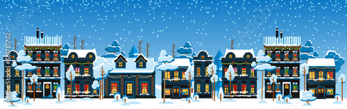 Cute Christmas and winter houses. Snowy night in cozy Christmas town city panorama. Winter village night landscape Christmas outdoor decorations.