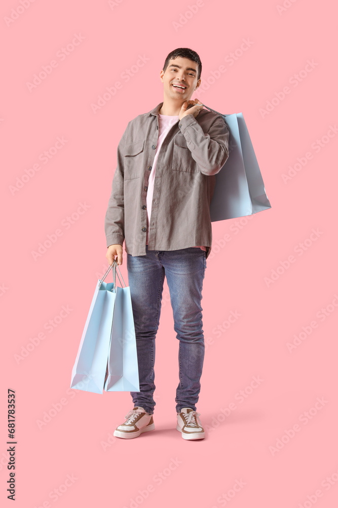 Happy young man with shopping bags on pink background Happy young man with shopping bags on pink background