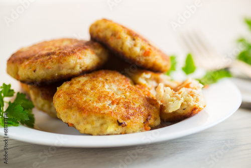 Cooked fried fish cutlets in a plate with herbs.