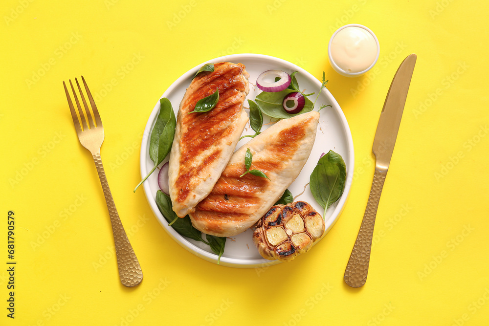 Plate of tasty grilled chicken breast with basil, garlic and red onion on yellow background Plate of tasty grilled chicken breast with basil, garlic and red onion on yellow background