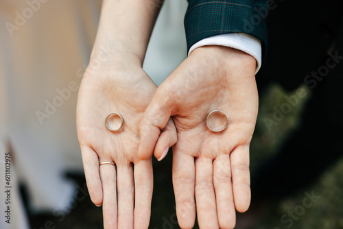 the bride and groom hold wedding rings in their hands