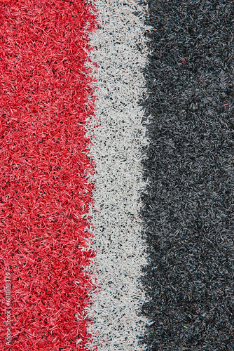 Red, white, and black streaks in vertical row Cardinals football team colors on fake grass abstract