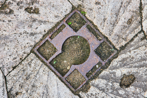 Abstract geometric pattern in dirty, textured concrete with metal center, background asset photo