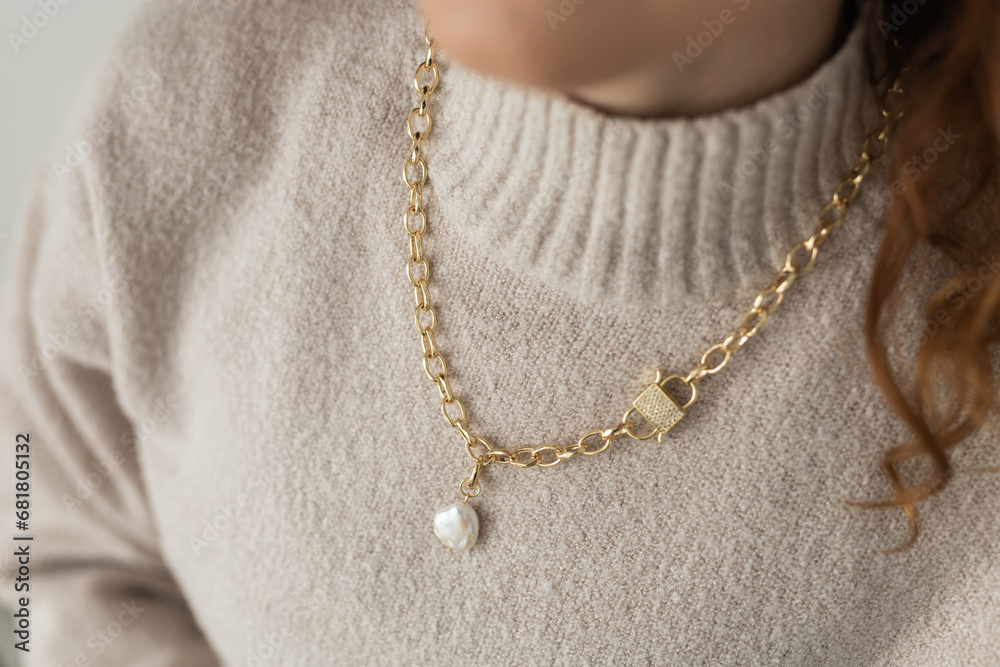 Close-up female in modern gold metal necklace chain with pearl pendant Close-up female in modern gold metal necklace chain with pearl pendant