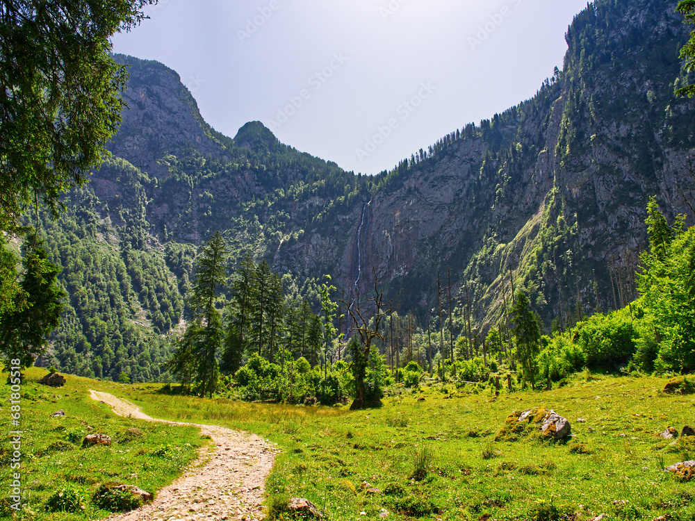 Footpath leading in mountain valey with waterfall landscape view