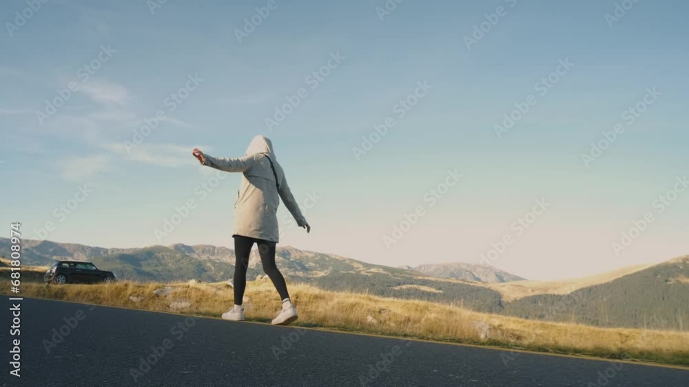 A beautiful young woman traveler walks along the most beautiful high mountain road in Romania Transalpina highway at morning. Transalpina, Carpathian mountains in Romania at sunrise A beautiful young woman traveler walks along the most beautiful high mountain road in Romania Transalpina highway at morning. Transalpina, Carpathian mountains in Romania at sunrise