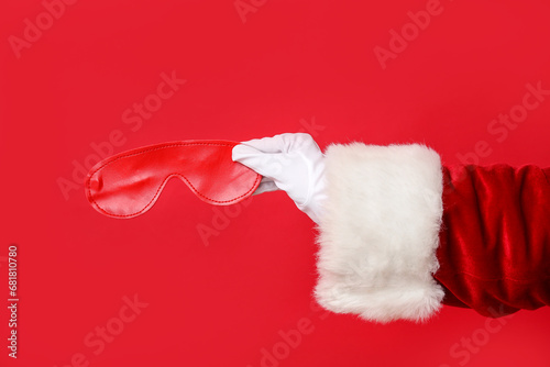 Santa hand with mask from sex shop on red background, closeup