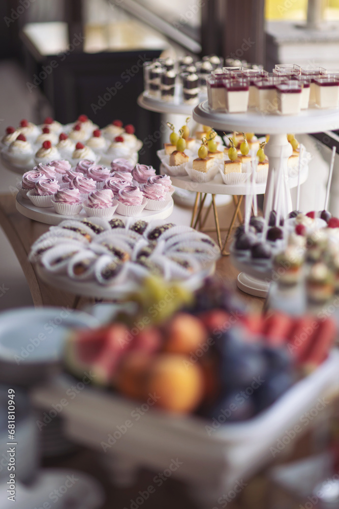 Closeup of many small cakes, sweets, fruits served on plate for cocktail party or shelves of store. Candy bar on birthday or wedding holiday dinner. catering food. tasty dessert. Wedding banquet table Closeup of many small cakes, sweets, fruits served on plate for cocktail party or shelves of store. Candy bar on birthday or wedding holiday dinner. catering food. tasty dessert. Wedding banquet table