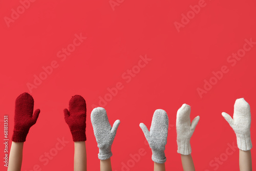 Female hands in stylish warm mittens on red background