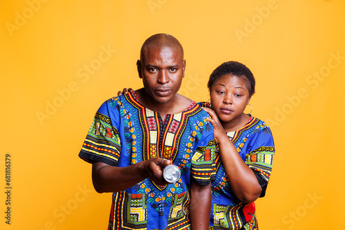 Confident man using flashlight and checking problem while terrified woman hiding behind back portrait. Anxious scared african american couple holding flash light and searching