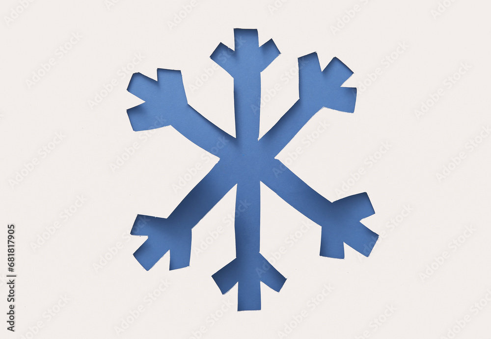 Fototapeta premium Cut white paper in shape of snowflake on blue background