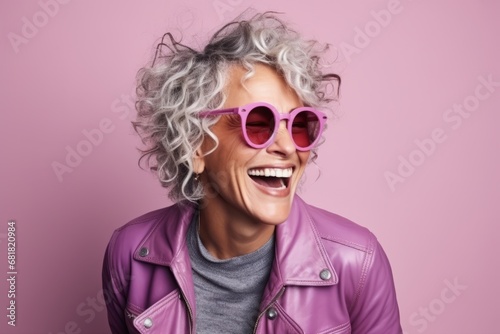 Portrait of a beautiful woman with curly hair and pink sunglasses over pink background