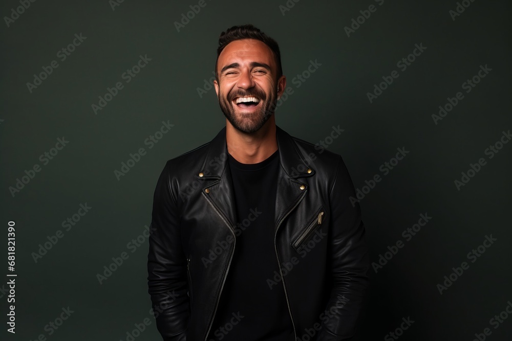 Portrait of a handsome man laughing while wearing a leather jacket on a dark background