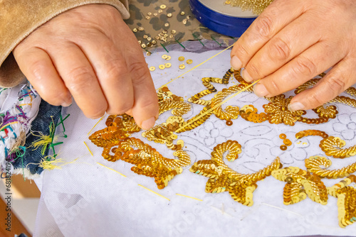 Vászonkép A Tunisian woman embroidering gold sequins onto white cloth.