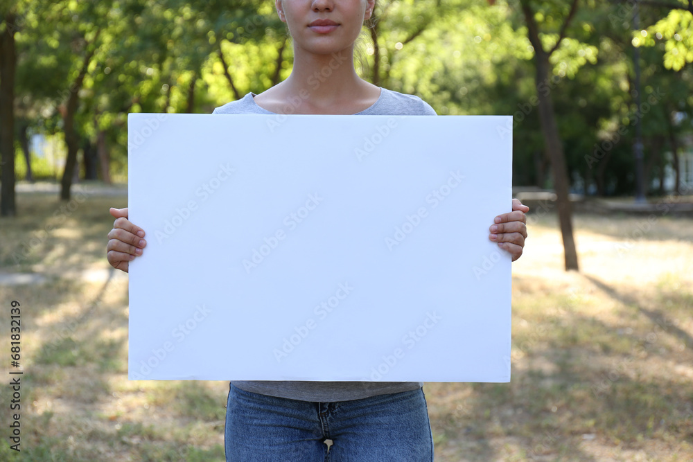 Woman holding blank poster outdoors, closeup. Mockup for design. Woman holding blank poster outdoors, closeup. Mockup for design.