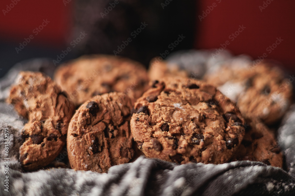 Fototapeta premium Chocolate chip cookies on red background and white napkin. Big close up view