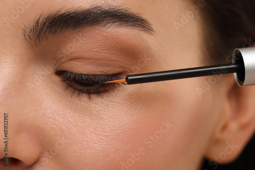 Woman applying serum onto her eyelashes, closeup. Cosmetic product © New Africa