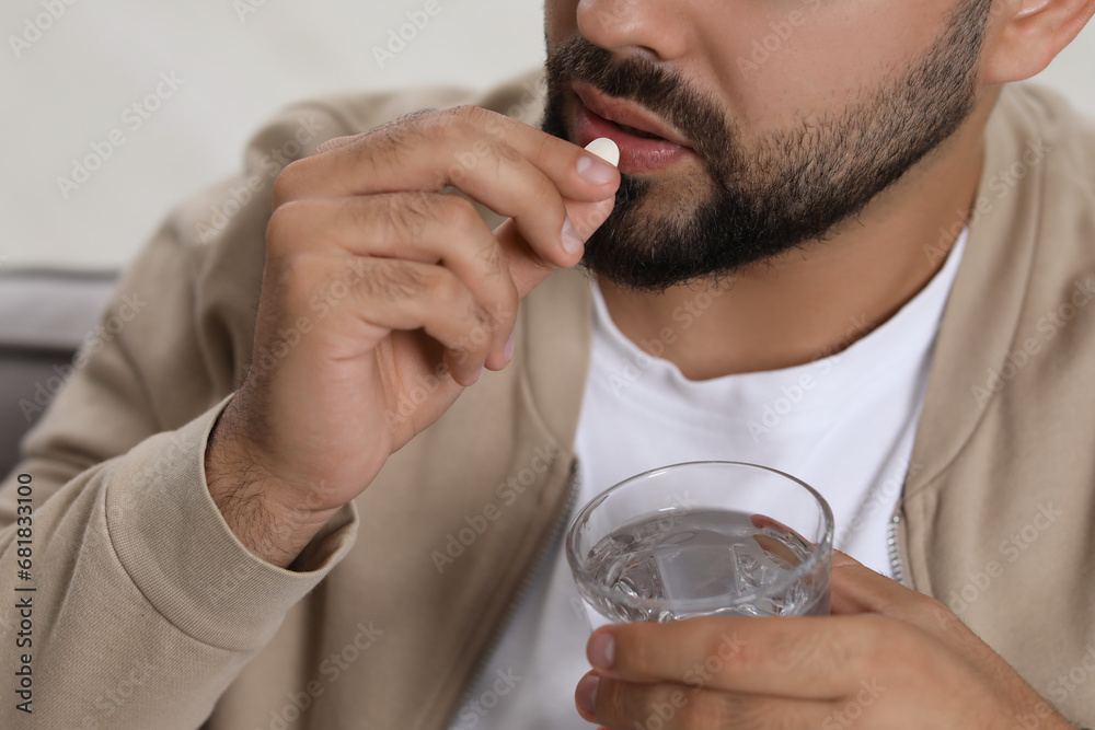 Man with glass of water taking antidepressant pill on blurred background, closeup Man with glass of water taking antidepressant pill on blurred background, closeup