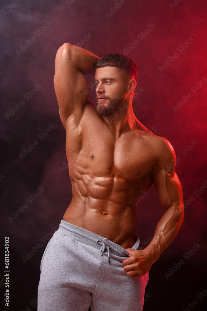 Fototapeta premium Young bodybuilder with muscular body in smoke on color background