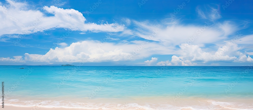 On my summer vacation in Thailand, I couldnt resist standing on the sandy beach with a stunning blue background of the ocean and sky, surrounded by the peaceful sounds of nature and the gentle waves
