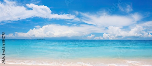 On my summer vacation in Thailand, I couldnt resist standing on the sandy beach with a stunning blue background of the ocean and sky, surrounded by the peaceful sounds of nature and the gentle waves