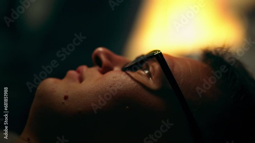 In the dark, a dreamer lies on the bed. A man, deep in thought, looks up, making plans for the next day. His eyes radiate energy and enthusiasm, as if charging for upcoming events photo