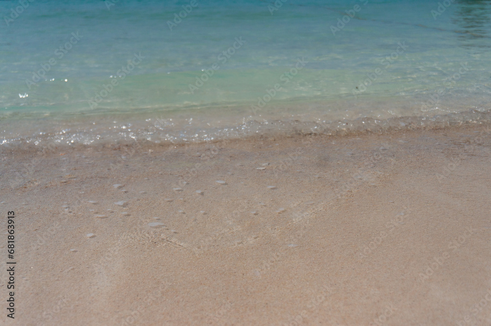 Soft turquoise sea waves on the sandy beach.