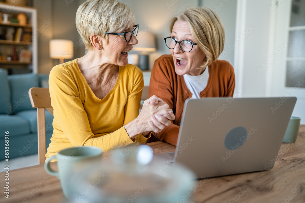 Senior women two females hold credit card online shopping at home Senior women two females hold credit card online shopping at home