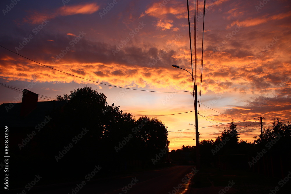 Red fiery sunset in a cloudy sky with city power lines in the background