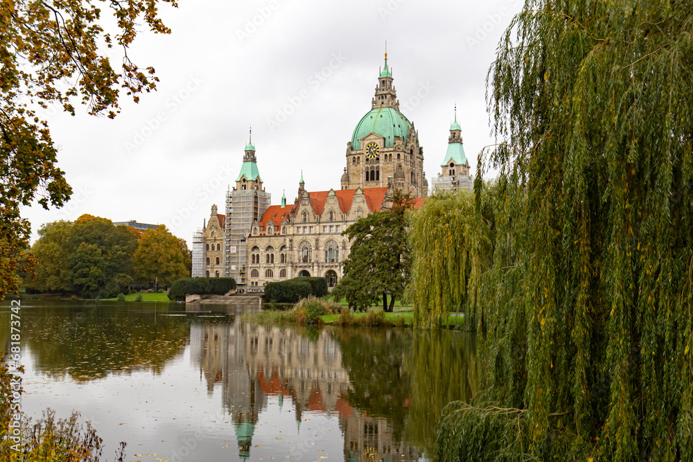 New City Hall in Hannover, Germany. Reflection in the water, trees (willows) near the lake New City Hall in Hannover, Germany. Reflection in the water, trees (willows) near the lake