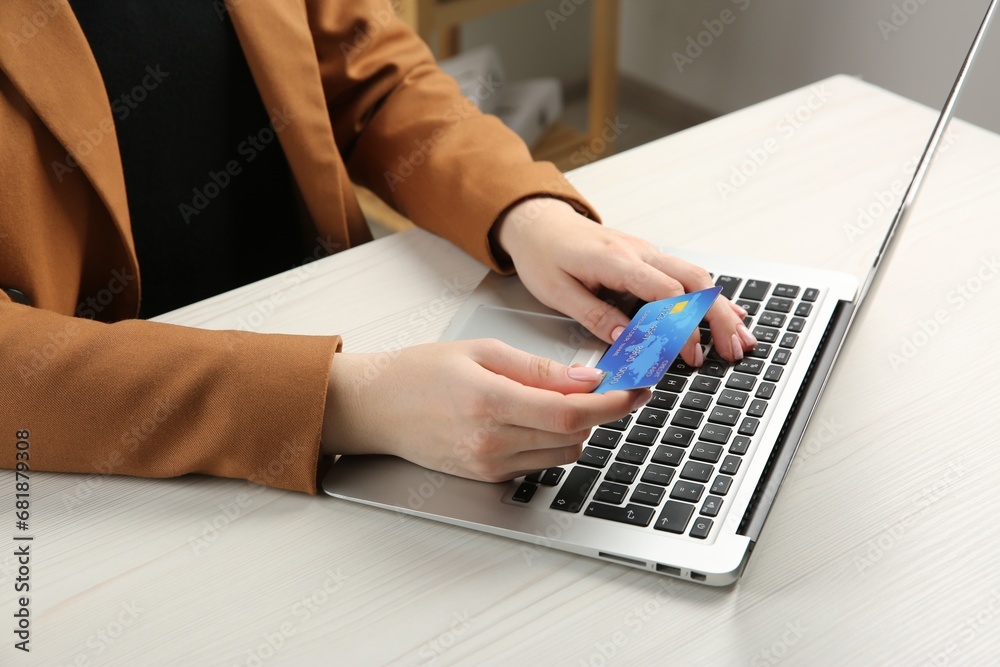 Online payment. Woman with credit card using laptop at white wooden table indoors, closeup Online payment. Woman with credit card using laptop at white wooden table indoors, closeup