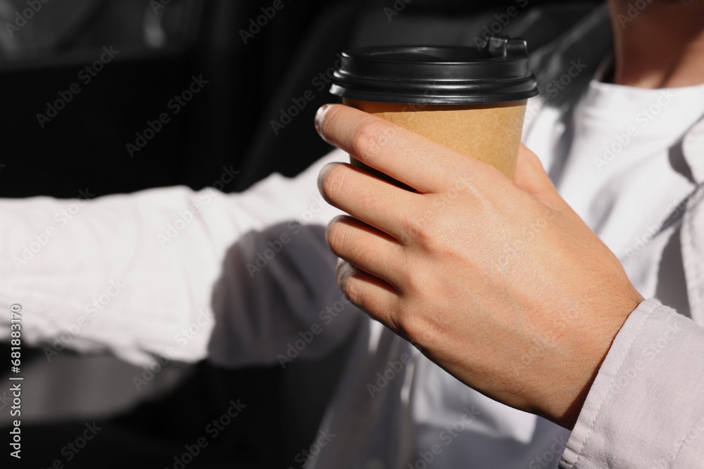Coffee to go. Man with paper cup of drink in car, closeup