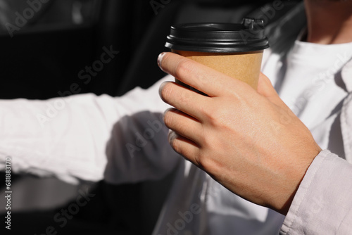Coffee to go. Man with paper cup of drink in car  closeup