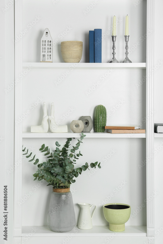 White shelves with books, eucalyptus and different decor indoors. Interior design White shelves with books, eucalyptus and different decor indoors. Interior design