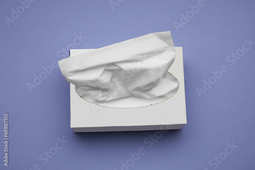 Box of paper tissues on purple background, above view