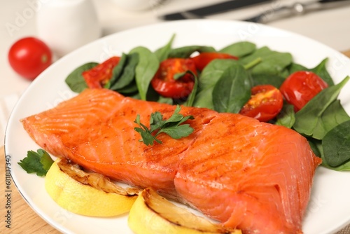 Foto Tasty grilled salmon with basil, tomatoes and lemon on table, closeup