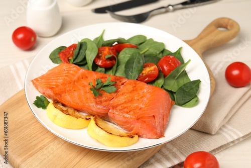 Tasty grilled salmon with basil, tomatoes and lemon on table