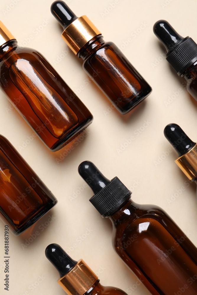 Many bottles with face serums on beige background, flat lay Many bottles with face serums on beige background, flat lay