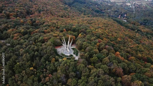 Aerial orbit shot of Monument to the Fallen Fighters of Kosmaj and a townscape in the background