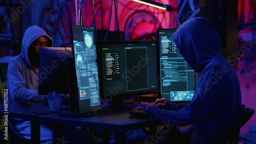 African american hacker and asian colleague working together in hidden place with graffiti walls, deploying malware on unsecured computers to steal sensitive data from unaware users online photo