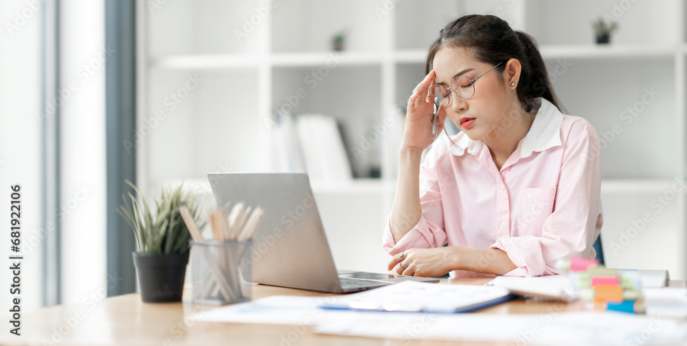Young busy stressed upset Asian businesswoman feeling tired frustrated, sitting at office desk,