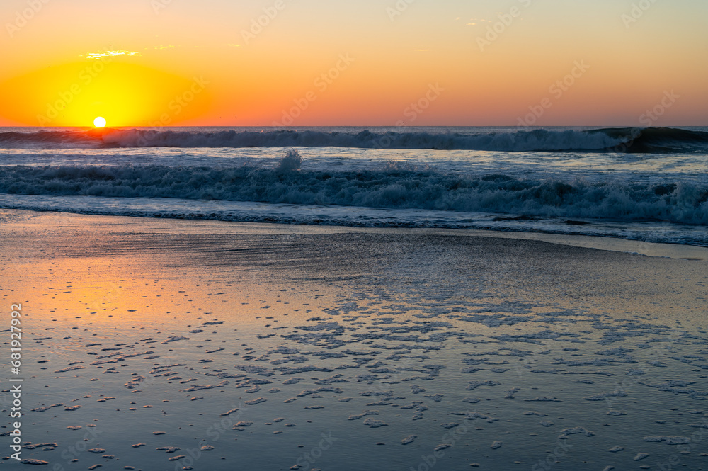 Fototapeta premium Beach Sunrise with reflection on sand and Sea foam (sun on left)