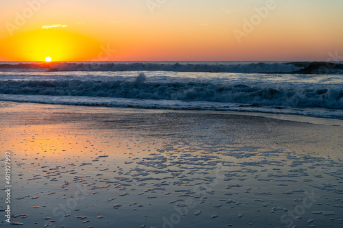 Beach Sunrise with reflection on sand and Sea foam  sun on left 
