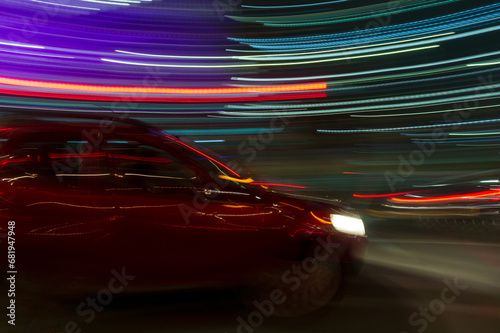 motion photo of red car moving through traffic at night 