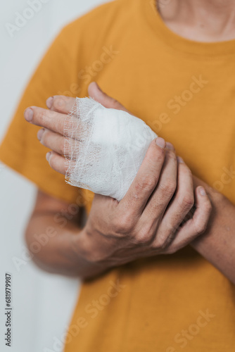 An individual wearing a yellow shirt with their left hand wrapped in a white bandage, possibly indicating an injury.