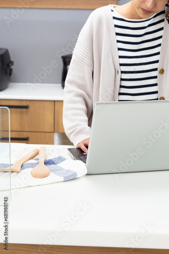 キッチンでパソコンを使う女性 © years
