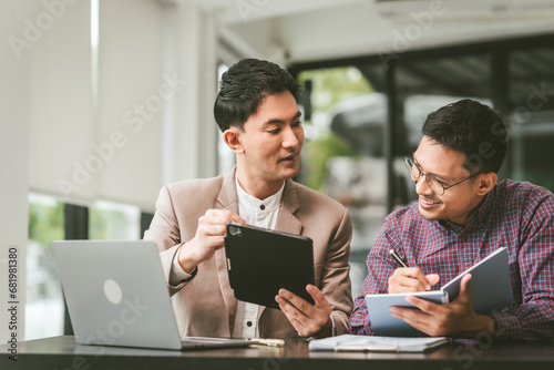Two professionals in meeting, one presenting "Business, Plan, Success" on whiteboard, another observing and holding a clipboard. Asian businessman, Colleagues, Middle-age © Ratirath