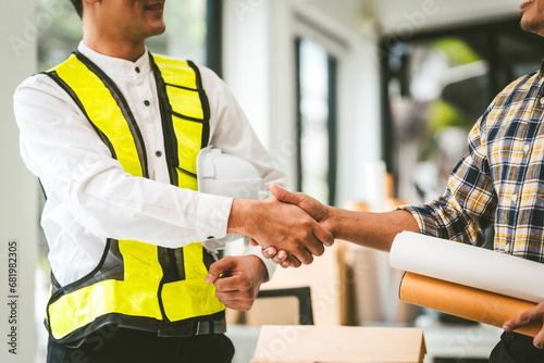 Two men engineer housing team meeting, one in safety vest holding color swatches, discussing plans, engineers architects talking house design color. Choosing paint for exterior and interior walls